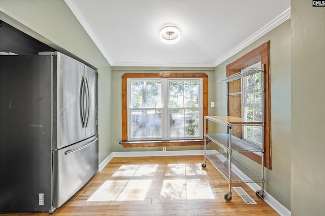 interior space featuring freestanding refrigerator, baseboards, a healthy amount of sunlight, and crown molding