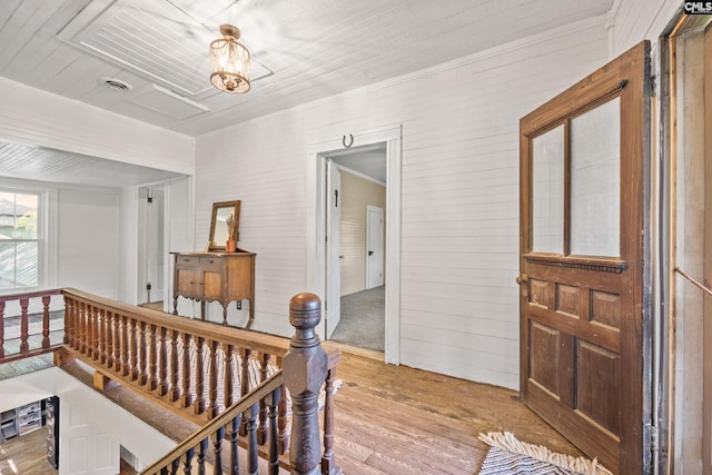 hall with crown molding, wood walls, an upstairs landing, and hardwood / wood-style flooring