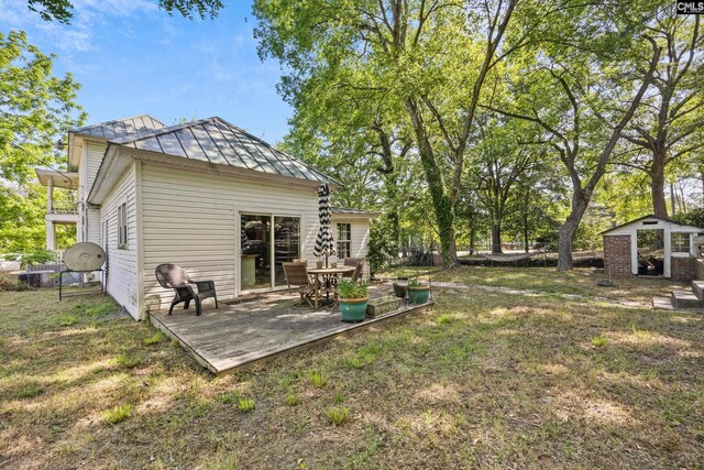 view of yard featuring fence, a wooden deck, and an outbuilding