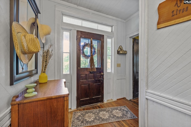 entryway with crown molding, a wealth of natural light, wood walls, and wood finished floors