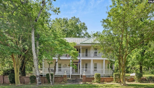 back of property with covered porch, metal roof, a standing seam roof, and a balcony