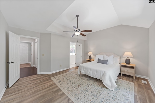 bedroom with light wood finished floors, lofted ceiling, baseboards, and ceiling fan