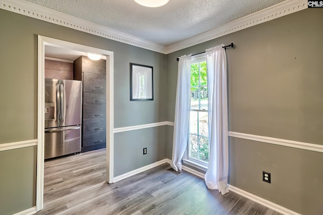 interior space with a textured ceiling, wood finished floors, and baseboards
