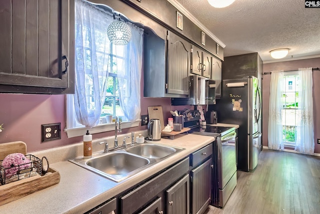 kitchen featuring stainless steel appliances, a textured ceiling, plenty of natural light, a sink, and light countertops