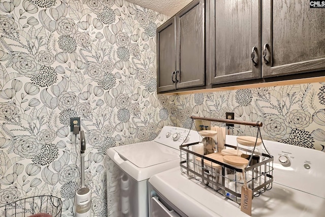 clothes washing area with a textured ceiling, washing machine and dryer, wallpapered walls, and cabinet space