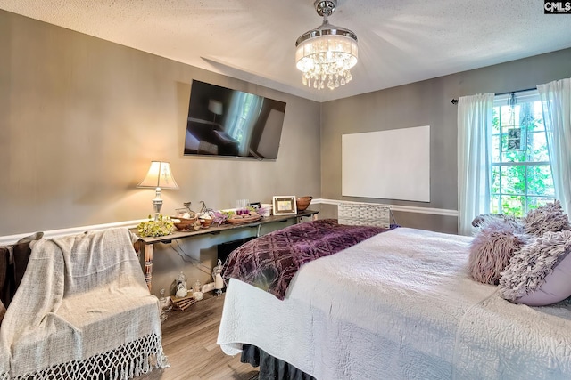 bedroom with a chandelier, a textured ceiling, and wood finished floors