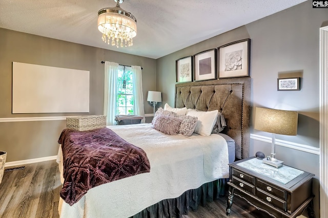 bedroom with a chandelier, wood finished floors, and baseboards