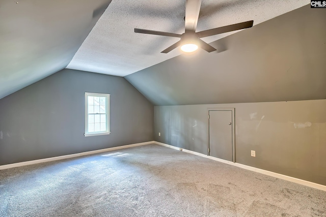 bonus room featuring a ceiling fan, a textured ceiling, baseboards, vaulted ceiling, and carpet floors