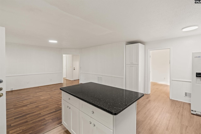 5227 Bush River Rd, Columbia, SC 29212 - kitchen with white cabinets, light wood-style floors, a center island, open floor plan, and dark stone counters