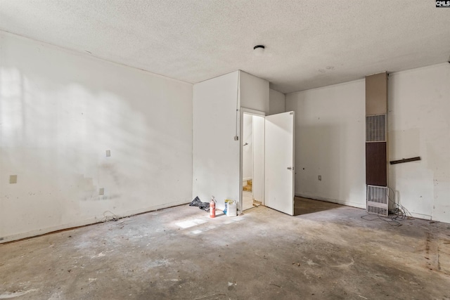 5227 Bush River Rd, Columbia, SC 29212 - spare room featuring unfinished concrete floors, a heating unit, and a textured ceiling