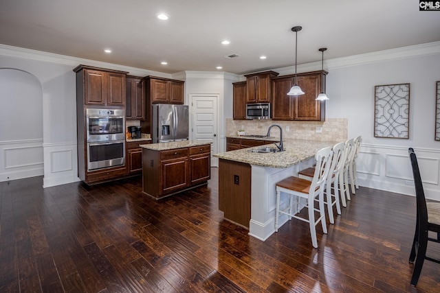 kitchen featuring a peninsula, stainless steel appliances, a kitchen breakfast bar, dark wood finished floors, and crown molding