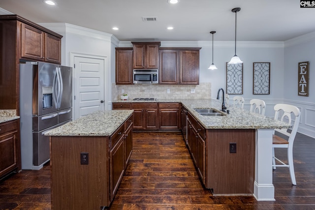 kitchen with stainless steel appliances, a peninsula, dark wood finished floors, and a sink