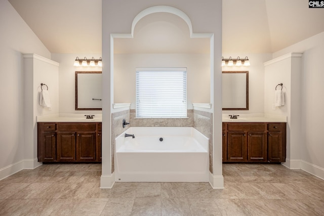 full bathroom featuring a sink, lofted ceiling, two vanities, and a bath