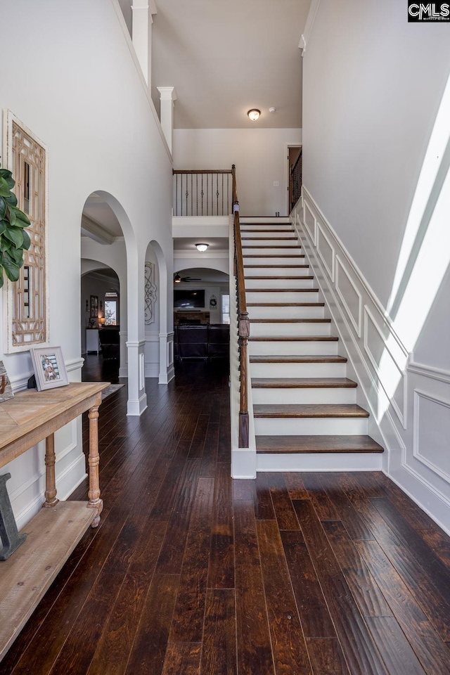 stairs featuring hardwood / wood-style flooring, a high ceiling, and arched walkways
