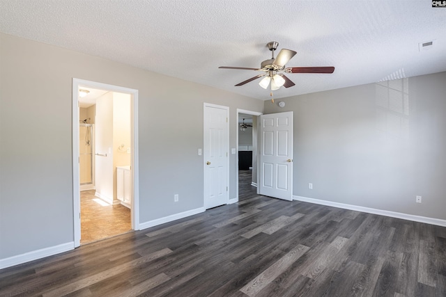 unfurnished bedroom featuring a textured ceiling, baseboards, dark wood-style floors, and visible vents