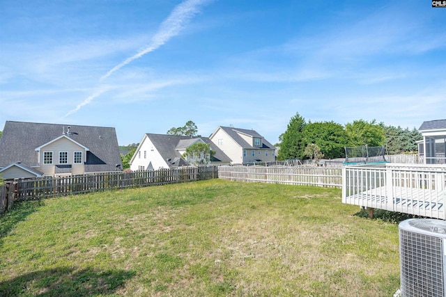 view of yard featuring a trampoline, a fenced backyard, and central AC