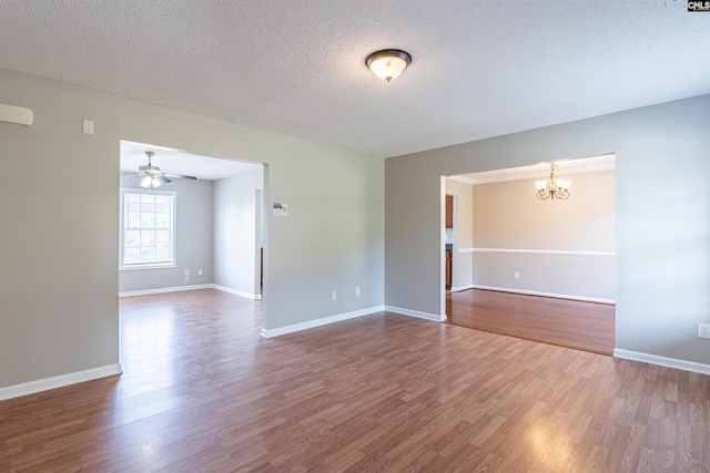 empty room featuring baseboards, dark wood-style flooring, a textured ceiling, and ceiling fan with notable chandelier
