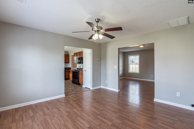 spare room featuring baseboards, dark wood-style flooring, visible vents, and ceiling fan