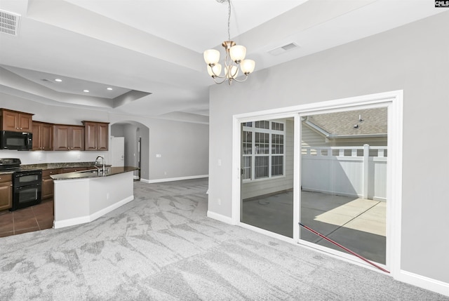 kitchen featuring an inviting chandelier, dark countertops, black appliances, arched walkways, and light colored carpet