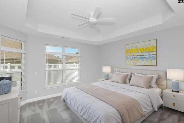 bedroom with baseboards, ceiling fan, visible vents, a raised ceiling, and carpet floors