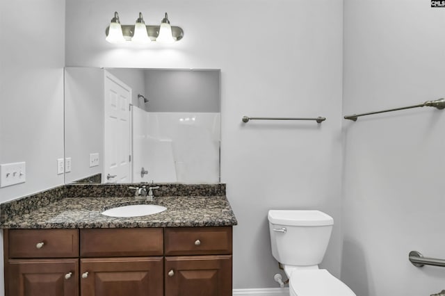 bathroom with toilet, walk in shower, vanity, and baseboards