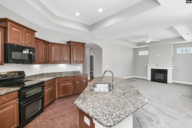 kitchen featuring a sink, black appliances, arched walkways, a ceiling fan, and a raised ceiling