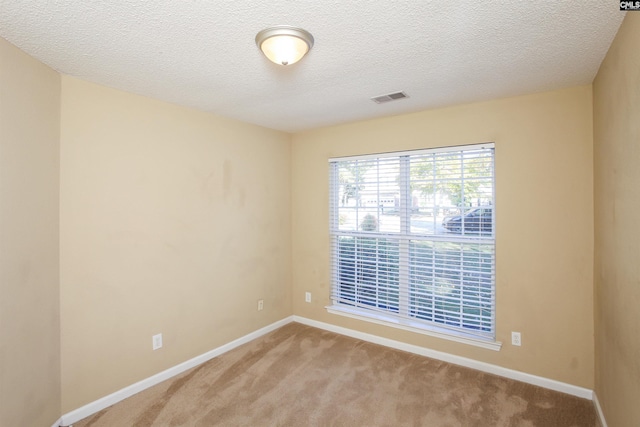 unfurnished room with light carpet, a textured ceiling, baseboards, and visible vents