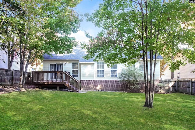 rear view of property featuring a lawn, a wooden deck, and a fenced backyard