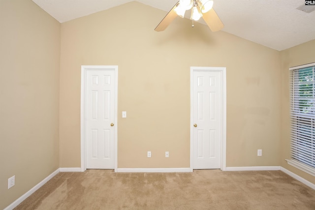 unfurnished bedroom with light colored carpet, vaulted ceiling, baseboards, and visible vents