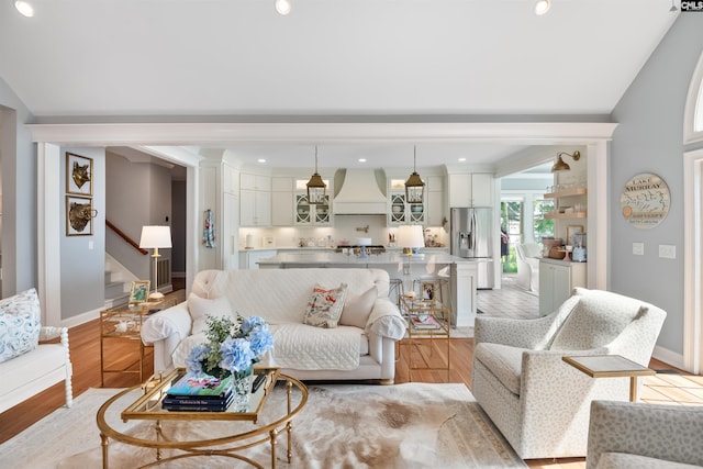 living area with stairway, baseboards, and light wood-style floors