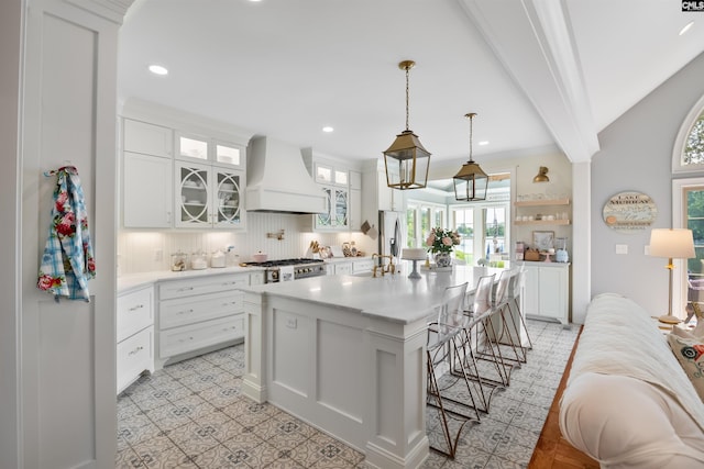 kitchen featuring a kitchen breakfast bar, a wealth of natural light, light countertops, and custom range hood