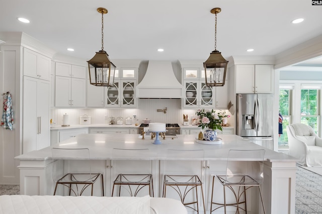 kitchen featuring premium range hood, range, stainless steel fridge, and white cabinets