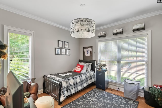 bedroom featuring wood finished floors, baseboards, and ornamental molding