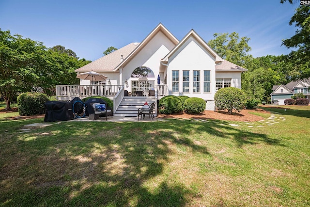 rear view of house with a lawn, a deck, stucco siding, and a patio