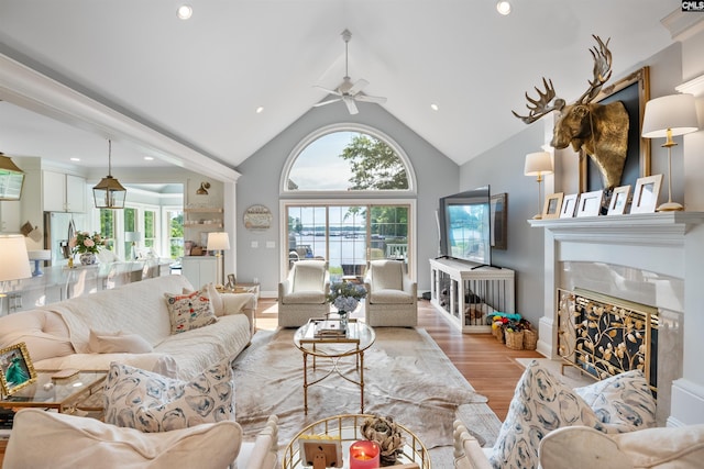 living area with a high end fireplace, high vaulted ceiling, recessed lighting, light wood finished floors, and a ceiling fan