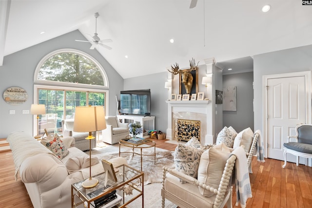 living area with a fireplace, ceiling fan, wood-type flooring, and high vaulted ceiling