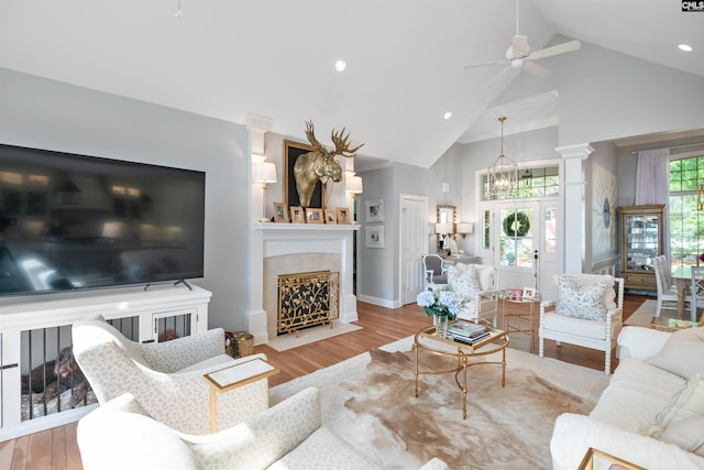 living room featuring a ceiling fan, a fireplace with flush hearth, high vaulted ceiling, and wood finished floors