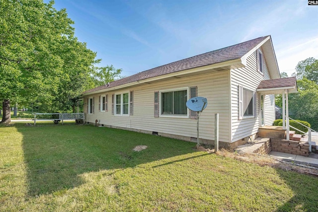 back of property with a shingled roof, a yard, and fence