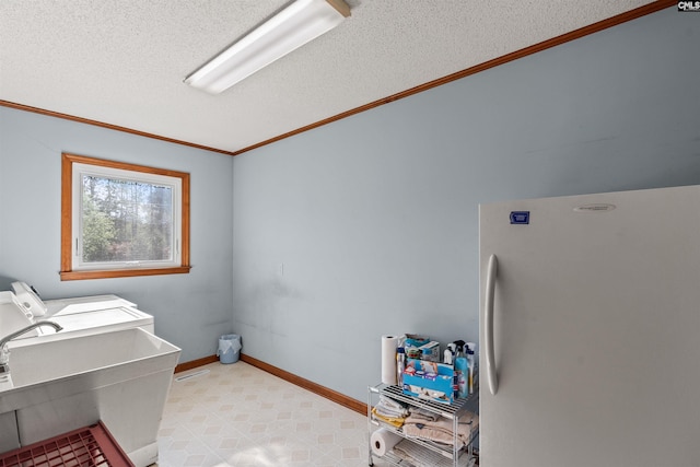 washroom with a sink, laundry area, a textured ceiling, crown molding, and washing machine and dryer