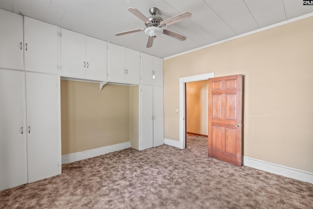 unfurnished bedroom featuring a closet, carpet, crown molding, ceiling fan, and baseboards