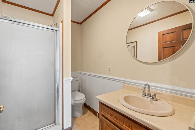 full bath with toilet, vanity, a textured ceiling, a stall shower, and wainscoting
