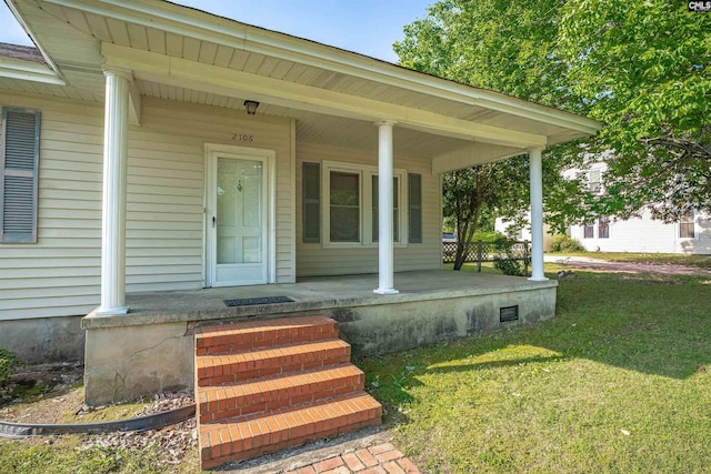 entrance to property featuring covered porch and a lawn