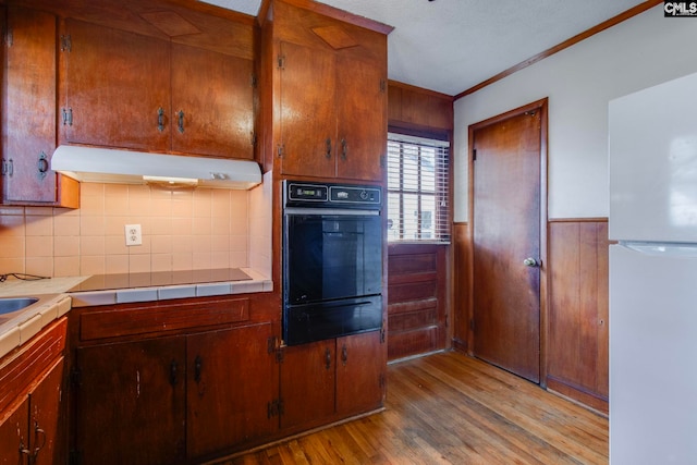 2700 Magnolia St, Columbia, SC 29204 - kitchen featuring tile countertops, under cabinet range hood, a warming drawer, black appliances, and light wood-type flooring