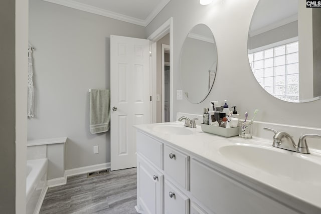 bathroom with a sink, crown molding, visible vents, and wood finished floors