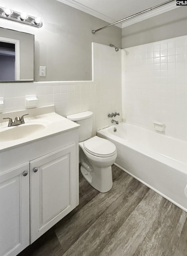bathroom featuring tile walls, toilet, wood finished floors, vanity, and ornamental molding
