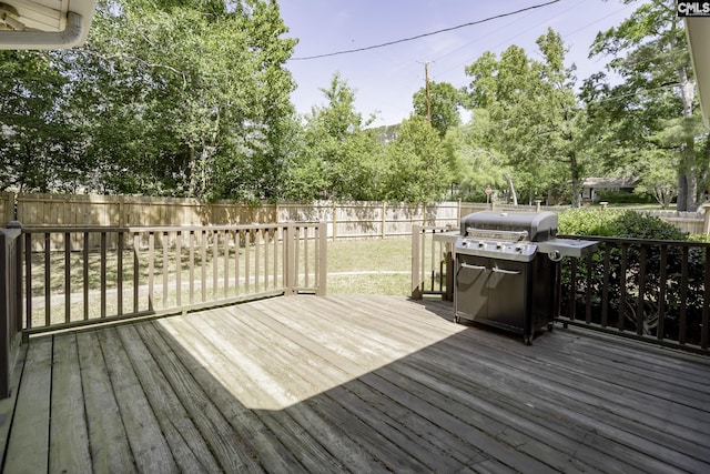 wooden terrace featuring a grill, a yard, and a fenced backyard