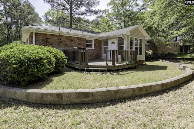 rear view of house featuring a yard, brick siding, and a wooden deck