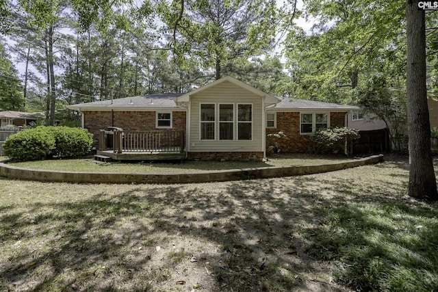 rear view of property with fence, a deck, and brick siding