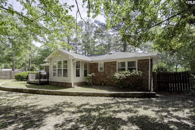 back of house featuring fence, brick siding, and a deck