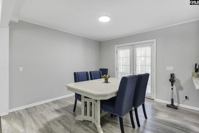 dining room featuring ornamental molding, baseboards, and wood finished floors